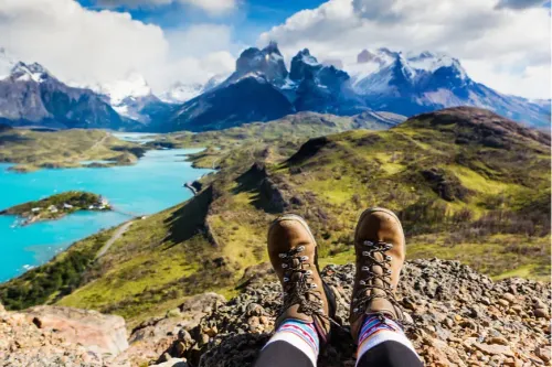 hiking boots in front of mountain and lake.